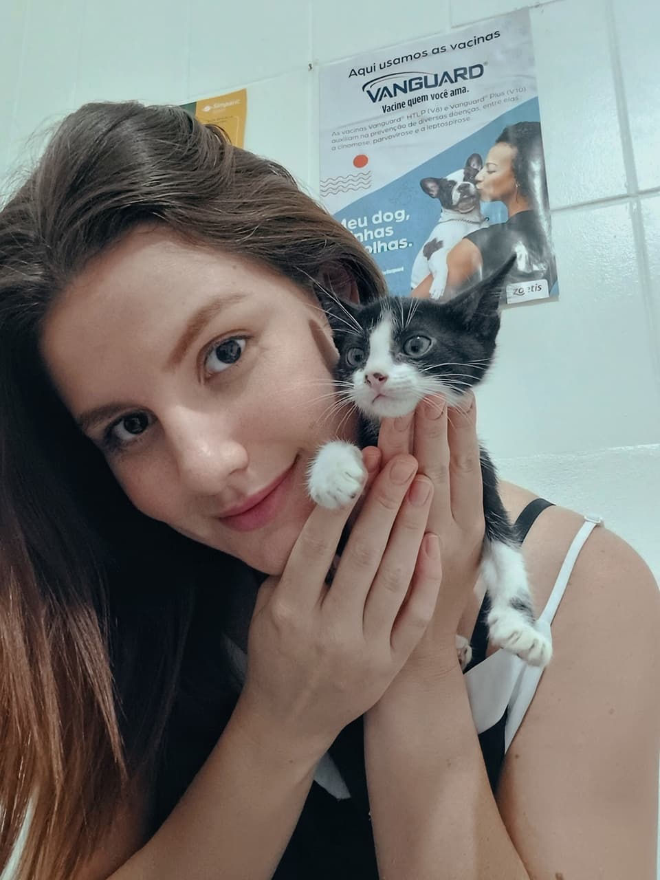Dra. Leticia Alves segurando um gatinho filhote com carinho em ambiente clínico